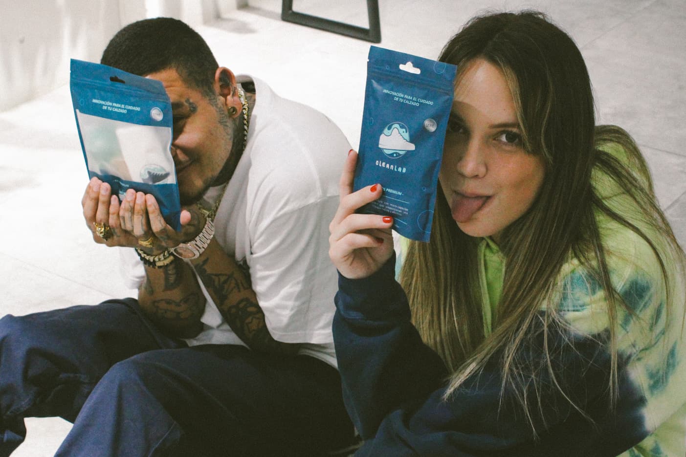 Dos personas mostrando productos de limpieza para calzado Clean Lab en un ambiente casual. Imagen que refleja el estilo juvenil, creativo y moderno de la marca especializada en cuidado de zapatillas.